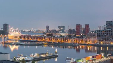 Güneş doğmadan önce Maashaven 'daki kuleler üzerindeki hava manzarası demirli gemilerle, Katendrecht ve Maas Nehri' yle, Rotterdam 'la geçiş zamanlarını gösteriyor. Aydınlatılmış fabrika ofis ve olay alanına dönüştürüldü