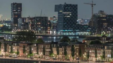 Geceleri Katendrecht yarımadasının panoramik zaman çizelgesi, Hollanda Rotterdam 'daki Maashaven limanı ve nehri. Aydınlatılmış şehir silüeti, modern gökdelenler ve geleneksel rıhtım evleri