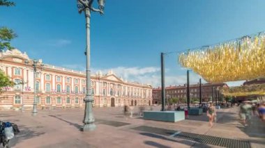 Capitole de Toulouse zaman çizelgesini gösteren panorama, Fransa 'nın Toulouse şehrinin tarihi belediye binasını ve belediye merkezini gösteriyor. Capitole Meydanı' nda mavi bulutlu gökyüzü altında birçok restoran bulunuyor.