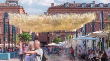 Fransa 'nın Toulouse şehrinde Capitole Meydanı' nda. İkonik kırmızı tuğlalı tarihi ön cephelerde açık hava kafeleri, beyaz şemsiyeler ve süslemeli ışıklandırmalar var. Canlı bir yaya istikameti.