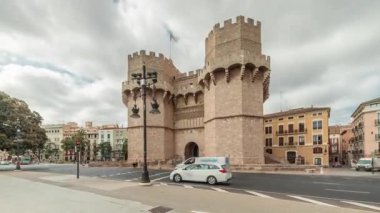 Serrans Kuleleri Torres de Serranos zaman atlaması. Valencia, İspanya 'da. Şehrin antik duvarlarından gelen büyük bir ortaçağ kapısı. Bulutlu bir gökyüzü altında hareketli bir sokak manzarası bu tarihi yeri çerçeveler.