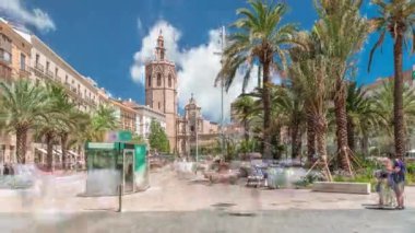 Valencia, İspanya 'da Plaza de la Reina' nın panoramik zaman atlaması. Tarihi bir kilise kulesi, hareketli kafeler ve sıcak Akdeniz semaları altında palmiyeleri olan merkezi bir çeşme..