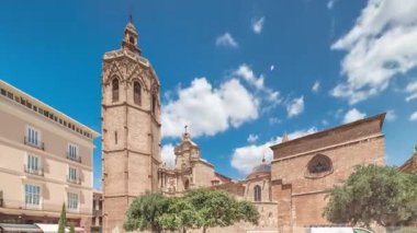 Valencia, İspanya 'da Plaza de la Reina' nın panoramik zaman atlaması. Tarihi bir kilise kulesi, hareketli kafeler ve sıcak Akdeniz mavi bulutlu gökyüzünün altında merkezi bir çeşme ile dolu canlı bir meydan..