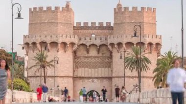 Serrans Kuleleri Torres de Serranos zamanapse Valencia, İspanya 'da. Şehrin antik duvarlarından gelen büyük bir ortaçağ kapısı. İnsanlar gün batımından önce tarihi bir dönüm noktasında köprüde yürüyorlar.