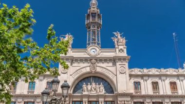 Valensiya 'daki tarihi posta ofisi Palau de les Comunicacions Belediye Meydanı Plaza del Ayuntamiento' da. Süslü cephe, yeşil ağaçlar ve İspanya şehir merkezinde mavi bir gökyüzü..