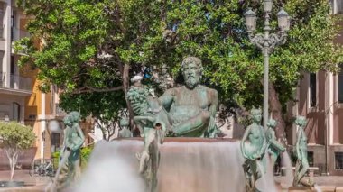 Valencia, İspanya 'daki ikonik Turia Pınarı ile birlikte Plaza de la Virgen' den Timelapse. Neptün heykeli Turia Nehri ve kanallarını temsil eder. İnsanlar yeşil ağaçlarla meydanda geziniyor.