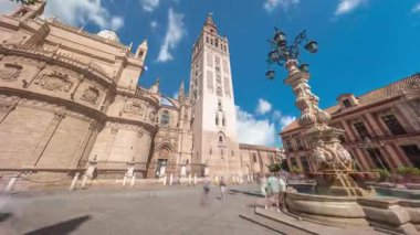 Virgen de los Reyes Meydanı, Seville Katedrali ve Giralda Kulesi zaman atlamalı Seville, İspanya 'da. Dünyanın en büyük gotik katedrali, mavi bulutlu gökyüzünün altındaki UNESCO miras alanı.
