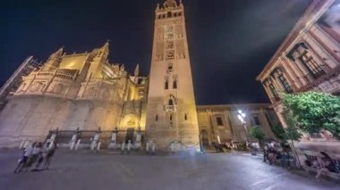 La Giralda ve Seville Katedrali geceleri aşırı hızlanarak altın ışıklarla parıldıyor. Tarihi çan kulesi, gotik detaylar ve aydınlatılmış sokaklar Sevilla, İspanya 'da büyülü bir atmosfer yaratıyor.