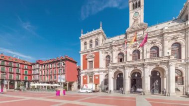 Panorama, Valladolid Plaza Belediye Başkanı Timelapse bayraklarıyla belediye binasının ön cephesini gösteriyor. Mavi gökyüzü ve şehrin göbeğindeki tarihi mimari. Yayalar bu merkez meydandan geçiyor..