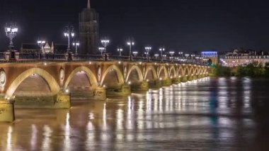Fransa 'nın Bordeaux kentindeki Porte de Bourgogne' un aydınlatıldığı, gece Garonne Nehri üzerinde süslenmiş sokak lambaları olan Pont de Pierre Stone Köprüsü. Yansımaların ve şehir ışıklarının çarpıcı zamanlaması