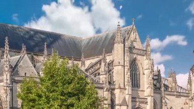 Bordeaux, Fransa 'daki Basilique Saint-Michel zaman çizelgesi, yüksek kulesi olan gotik bir simgedir. İnsanlar yakındaki kafeleri seviyor, yeşil ağaçların altında ve mavi bulutlu gökyüzü, şehrin canlı cazibesini yakalıyor.