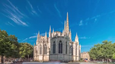Saint-Andre de Bordeaux Katedrali. Mavi gökyüzünün altında ikiz kuleleri olan hızlandırılmış zaman atlaması. Yeşil ağaçlar ve meydanda yürüyen insanlar sakin bir şehir atmosferi yaratıyor. Bordeaux, Fransa