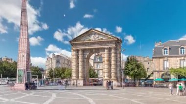 Fransa, Bordeaux 'da Place de la Victoire' da Porte dAquitaine kemeri ve dikilitaş. Tramvay hatları, kafeler ve mavi bulutlu gökyüzünün altında çevreleyen canlı Bordeaux 'nun tarihi simgesi.