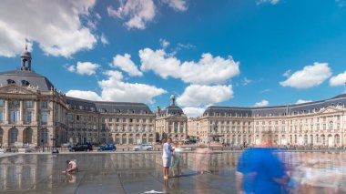 Place de la Bourse ve Miroir d 'eau hiperlapse Bordeaux, Fransa' da, tarihi mimariyi yansıtıyor. Turistler şehir simgesi ve çeşmenin tadını çıkarıyorlar. Trafik ve tramvay zamanı geçiyor..