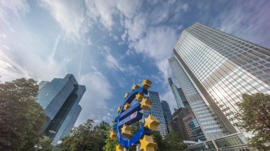 Avrupa Merkez Bankası 'nın eski genel merkezi yakınlarındaki Frankfurt şehir merkezinde Avrupa para birimi tabelasının zaman aşımına uğraması. Güneş ışığı bulutlu bir gökyüzünde gökdelenlerden yansıyor. Almanya