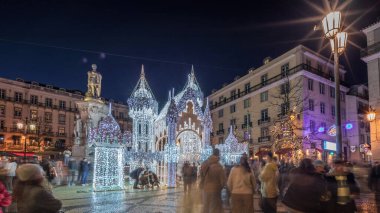 Lizbon, Portekiz 'deki Luis de Camoes meydanında aydınlatılmış şatoyla Noel süslemelerinin gece süreleri. İnsanlar şenlikli ışıkların ve tarihi mimarinin etrafında dolanıyor. Ön görünüm
