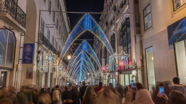 Lizbon şehir merkezindeki Chiado Carmo sokağındaki Noel ışıkları ve dekorasyonları gece aşırı hızlandı. İnsanlar aydınlanmış kemerlerin altında yürürler. Portekiz 'de festival dekorlu tatil atmosferi