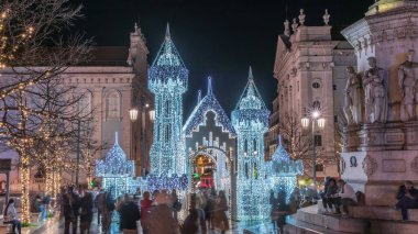 Lizbon, Portekiz 'deki Luis de Camoes meydanında aydınlatılmış şatoyla Noel süslemelerinin gece süreleri. İnsanlar festival ışıkları ve tarihi mimari etrafında yürüyorlar..
