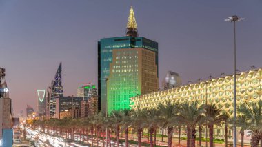 Suudi Arabistan, Riyad 'daki Kral Fahd Yolu' nun hava-gece zaman çizelgesi. Aydınlatılmış Riyad Ulusal Kütüphanesi yakınlarında modern kuleler ve gökdelenlerle çevrili araçlar ve taksilerle dolu.