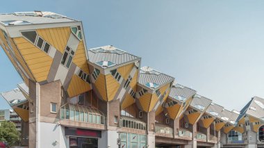 Rotterdam 'daki Küp Evi' nin (Kubuswoningen) hiperlapesi. Eşsiz sarı küp şekilli evler şehrin zaman dilimi içinde yenilikçi mimari sergiliyor. Mavi gökyüzü ve şehir canlılığı. Hollanda
