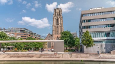 Laurenskerk 'in (Saint Lawrence Kilisesi) Grotekerkplein, Rotterdam' daki hiperlapesi. İnsanlar mavi bulutlu gökyüzünün altında çimlerde dinleniyorlar. Kanal merdivenlerinin yanında saati olan tarihi çan kulesi. Hollanda