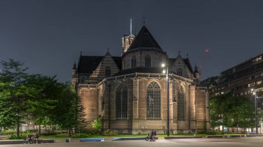Laurenskerk 'in (Saint Lawrence Kilisesi) geceleyin Rotterdam' da Grotekerkplein 'de yaptığı hiperlapse. Zaman ayarlı tarihi çan kulesiyle aydınlatılmış. Parktaki yeşil ağaçlar. Hollanda
