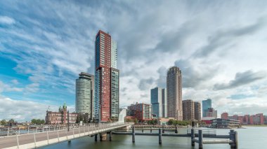 Hollanda, Rotterdam 'da bulunan ve yerel olarak Hoerenloper olarak bilinen Rijnhaven Köprüsü' nden Hiperlapse. Arka planda modern gökdelenleri ve bulutlu gökyüzü olan bir yaya ve bisiklet köprüsü