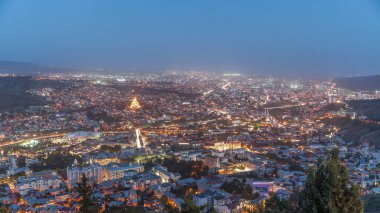 Alacakaranlıkta Tiflis şehri, Gürcistan 'dan gece geçiş zamanı. Şehir merkezinin ve Tiflis 'teki Kura Nehri' nin üst manzarası. Gün batımından sonra Gürcistan başkentinin havadan görünüşü