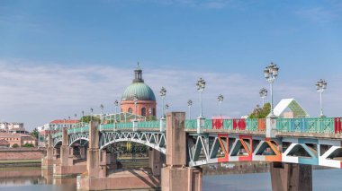 Garonne Nehri 'nin üzerindeki Saint Pierre Köprüsü' nde su ve La Grave Hastanesi 'nin arka planında bulutlu mavi bir gökyüzünün altında yansımaları var. Klasik sokak lambaları cazibe katar. Toulouse, Fransa