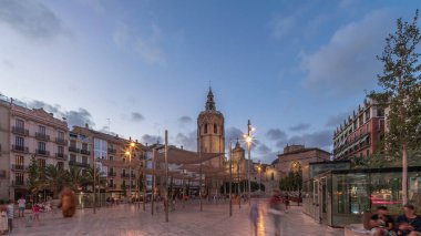 İspanya, Valencia 'daki Plaza de la Reina' da panoramik günden geceye geçiş süreleri aşırı hızlanıyor. Tarihi bir kilise kulesi, hareketli kafeleri ve akşam gökyüzünün altında merkezi bir çeşmesi olan canlı bir meydan..