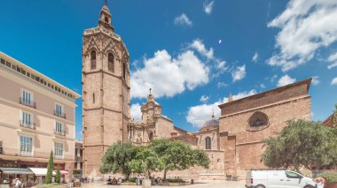 Valencia, İspanya 'da Plaza de la Reina' nın panoramik zaman atlaması. Tarihi bir kilise kulesi, hareketli kafeler ve sıcak Akdeniz mavi bulutlu gökyüzünün altında merkezi bir çeşme ile dolu canlı bir meydan..