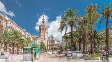 Valencia, İspanya 'da Plaza de la Reina' nın panoramik zaman atlaması. Tarihi bir kilise kulesi, hareketli kafeler ve sıcak Akdeniz semaları altında palmiyeleri olan merkezi bir çeşme..