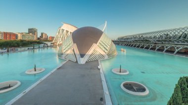 Valencia 'nın Sanat ve Bilim Şehri' nin çarpıcı zamansal hızlandırıcı gölgeleri fütüristik mimari üzerinde hareket ederken sakin suya yansıyor. Günbatımında büyüleyici İspanyol kültürel simgesi