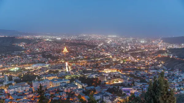 Alacakaranlıkta Tiflis şehri, Gürcistan 'dan gece geçiş zamanı. Şehir merkezinin ve Tiflis 'teki Kura Nehri' nin üst manzarası. Gün batımından sonra Gürcistan başkentinin havadan görünüşü