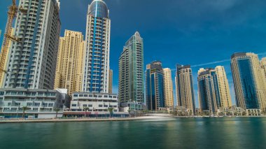 Dubai Marina Kuleleri, Birleşik Arap Emirlikleri 'ndeki gezinti güvertesi zaman aşımından suya yansıdı. Dubai Marina, Dubai 'de yer alan bir şehirdir. Mavi bulutlu gökyüzü
