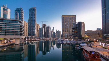 Dubai 'deki köprüden gece gündüz geçiş zamanı, Birleşik Arap Emirlikleri' ne ait kuleleri ve yatları olan Marina rıhtımı. Dubai Marina, Dubai 'de bir şehirdir.