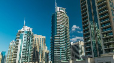 Dubai Marina Kanal Panorama 'sı yatları ve modern kuleleri ile Dubai' deki deniz kıyısından yansıtılan yeşil su, Birleşik Arap Emirlikleri. Yapay kanal ve gökdelenler