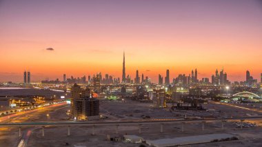 Dubai şehir merkezinin silüeti günden geceye geçiş zamanı. Çölde inşa edilmiş modern gökdelenlerin güzel gökdelenleri. Havaalanı yakınındaki binadan gün batımından sonra hava görüntüsü