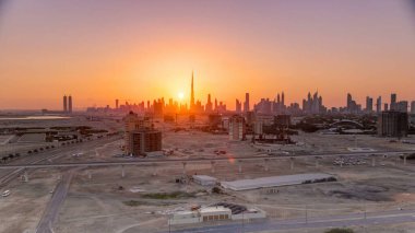 Akşam saatlerinde Dubai şehir merkezinin ufuk çizgisi ile gün batımı. Çölde inşa edilmiş modern gökdelenlerin güzel gökdelenleri. Havaalanı yakınındaki binadan hava görüntüsü