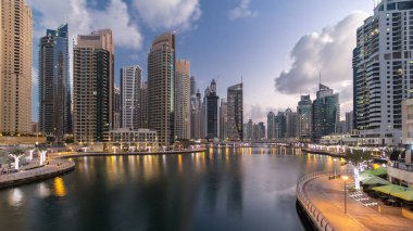 Dubai Marina Kanalı, modern kuleleri ve yatları olan liman kenti Dubai 'deki köprüden gece gündüz geçiş zamanı olan Birleşik Arap Emirlikleri' ne yansıyor. Güneş doğmadan önce etraftaki gökdelenler
