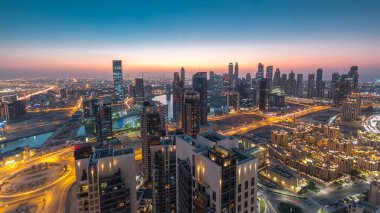 Günbegün modern şehrin hava manzarası trafik ve aydınlık gökdelenler ile geçiş zamanı, günbatımından sonra ofis binaları. İş Körfezi, Dubai, Birleşik Arap Emirlikleri.