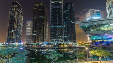 Rıhtımdaki ışıklandırılmış gökdelenlerin gece görüş açısını hızlandırın. Dubai, BAE 'deki Jumeirah Gölü Kuleleri' ndeki konut binaları. Balkondan hava görüntüsü