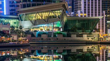 Rıhtımdaki gökdelenlere palmiyeli gece görüşü. Dubai, BAE 'deki Jumeirah Gölü Kuleleri' ndeki konut binaları. Rıhtımdan suya yansıyan görüntüyü göster