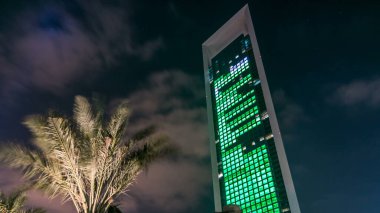 Geceleri iş yerlerindeki modern binaların zaman çizelgelerine bak. Parlak pencereli cam cepheli gökdelenler. Ekonomi ve finans kavramı. Abu Dabi, BAE