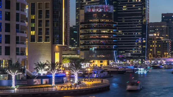 Dubai Marina rıhtımı kuleleri, rıhtımda restoranları ve Dubai 'deki köprüden geceye geçiş zamanı, Birleşik Arap Emirlikleri. Gün batımından sonra yapay kanallı bölge