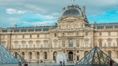 Ana kule müze binasının üstünde zaman ayarlı bir bayrak var. Paris, Fransa. Turistler gün batımından önce bulutlu gökyüzüyle gezerler