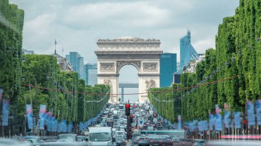 Arc de Triomphe, Champs Elysees 'yi yoğun bir trafik trafiğiyle izledi. Yeşil ağaçlar, yaz gününde bulutlu gökyüzü. Paris, Fransa