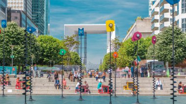 La Defansın gökdelenleri - modern iş yeri ve yerleşim alanı ve çeşme. Merdivenlerde oturan insanlar. Yeşil ağaçlar, güneşli yaz gününde mavi bulutlu gökyüzü. Paris, Fransa