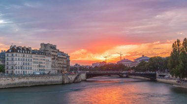 Günbatımında Le Pont D 'Arcole Köprüsü' nde insanlar ve tekneler zaman ayarlı, Paris, Fransa, Avrupa. Yaz günü Seine nehrinin yansımasıyla renkli bir gökyüzü. Arkaplanda vinçleri olan inşaat