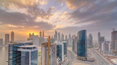 Dubai iş hangarı kuleleri, gün batımında hava zaman tüneli panoramasında. Bazı gökdelenlerin çatı manzarası ve inşaat halindeki yeni kuleler.